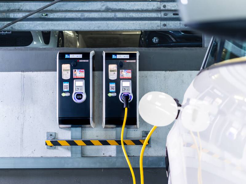 In einem Parkhaus sind zwei Ladestationen von Mennekes an der Wand montiert, an denen ein Elektroauto geladen wird.